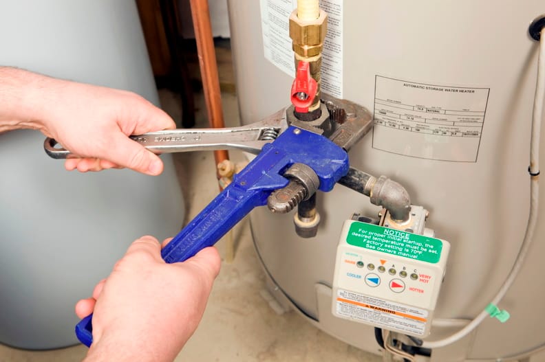 Plumber repairing water heater pipe connection in Athens, Georgia home