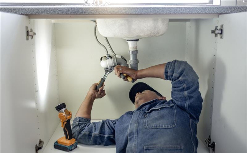 Plumber repairing kitchen sink drain pipes in Athens, Georgia