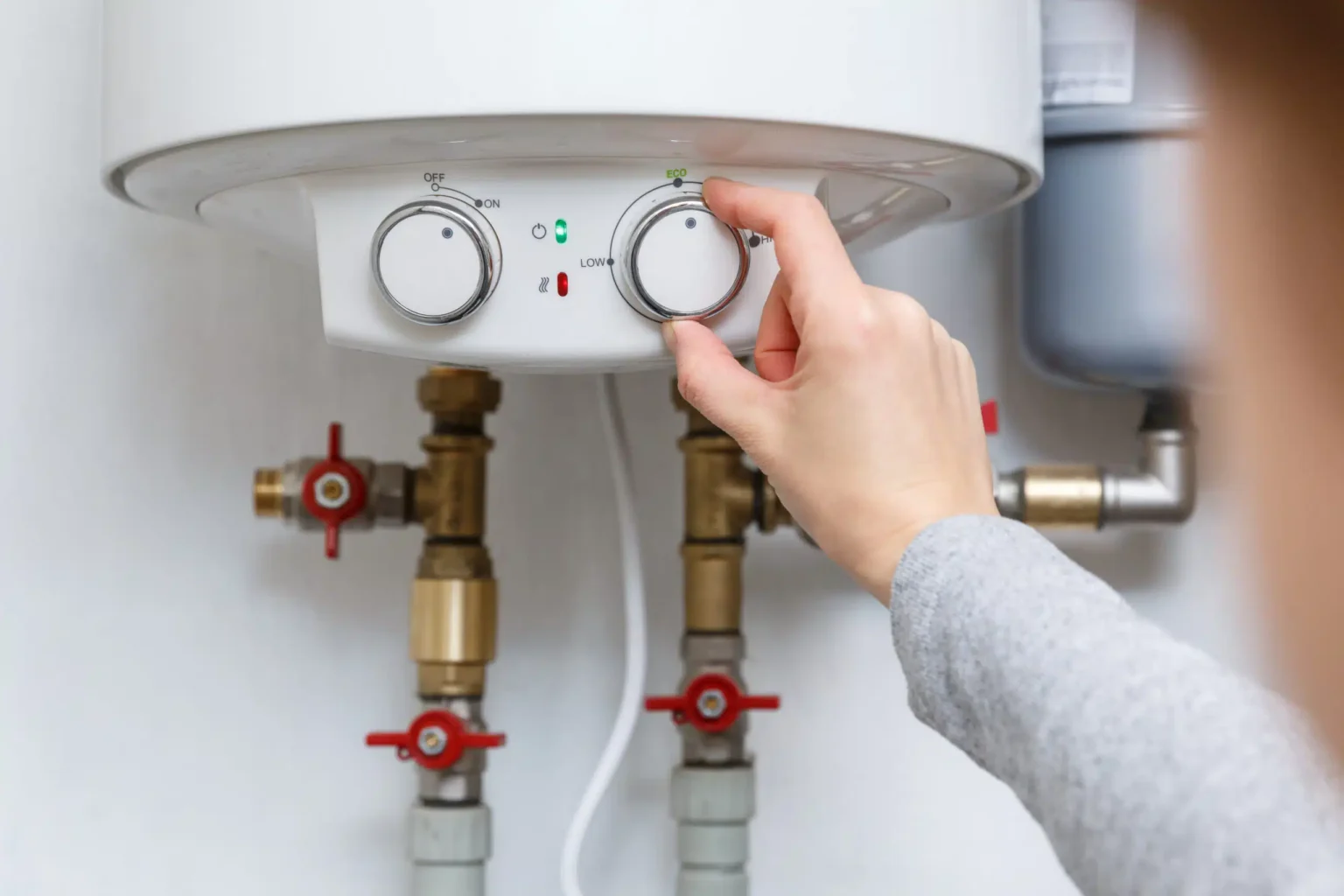 Homeowner adjusting the temperature controls on a water heater in Athens